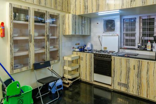 a kitchen with wooden cabinets and a stove at Belljem Homes -your own private resort -2 BHK GF in Trichūr
