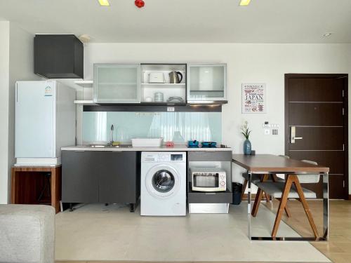 a kitchen with a washing machine and a table at THE ASTRA CONDO 2 BEDROOMS BY PING in Chiang Mai