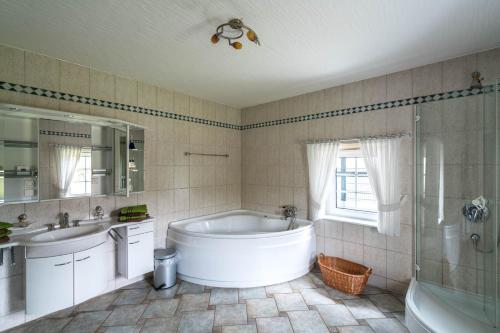 La salle de bains est pourvue d'une baignoire, de 2 lavabos et d'une douche. dans l'établissement Jagdschloss Stift Ennenbach, à Ruppichteroth