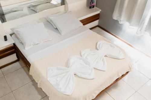 Una cama con sábanas blancas con arcos. en Hotel Avenida, en São João de Meriti