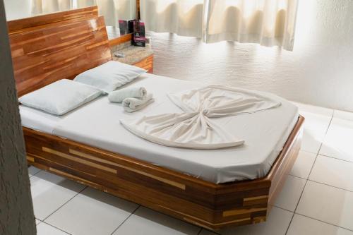 a bed with white sheets and a wooden headboard at Hotel Avenida in São João de Meriti