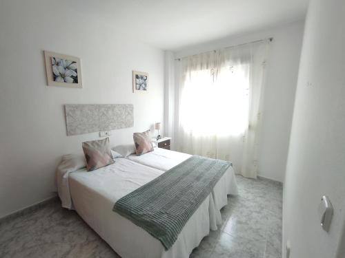 ein weißes Schlafzimmer mit einem Bett und einem Fenster in der Unterkunft Apartamentos JS Playa in Finestrat