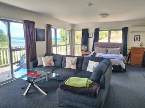 a living room with a couch and a bed at Tree House in Taieri Mouth