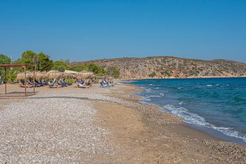 a beach with chairs and umbrellas and the ocean at Anesis Residence in Dhrepanon