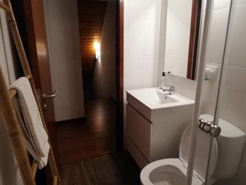 a bathroom with a white toilet and a sink at Casa Três Campos in Povoação