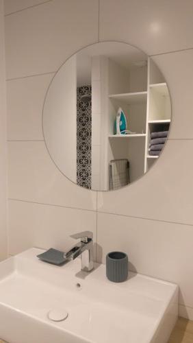 La salle de bains est pourvue d'un miroir sur un lavabo blanc. dans l'établissement Gite spacieux et cosy à la campagne proche de Strasbourg, à Achenheim