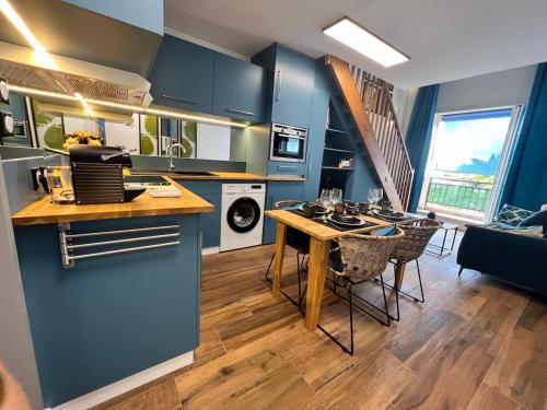 a kitchen with blue cabinets and a table with chairs at Le Pétrel Noir - Appartement sur la plage des Roches Noires à Saint-Gilles-les-Bains in Saint-Gilles les Bains