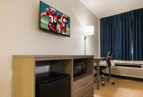 a room with a desk and a tv on a wall at Red Roof Inn Lawrenceburg in Lawrenceburg