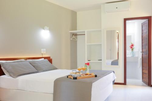 a bedroom with a white bed and a table at Brasil Tropical Village in Pipa