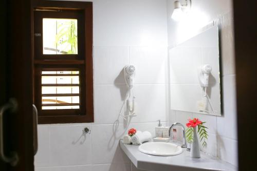 a white bathroom with a sink and a mirror at Brasil Tropical Village in Pipa