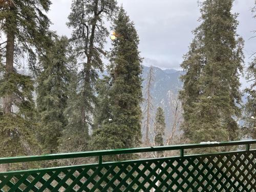 a fence with trees and mountains in the background at Umda Hotel Montana in Ayubia