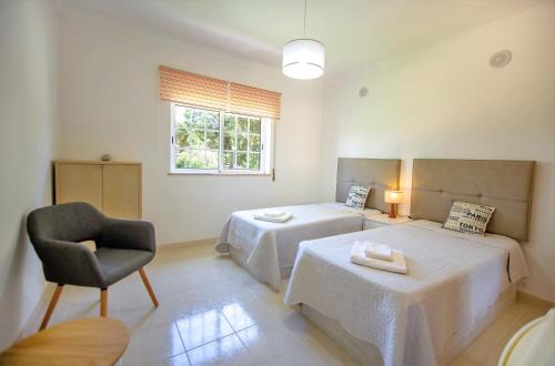 a bedroom with two beds and a chair and a window at ALFELI-AP in Olhos de Água