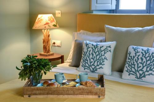 a bed with a tray of bread and a table with a lamp at Cactus Hydra - Art Apartments in Hydra