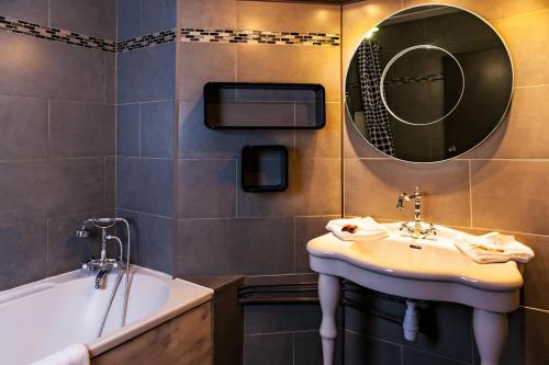 a bathroom with a sink and a tub and a mirror at Hôtel Restaurant du Château de la Tour in Béguey