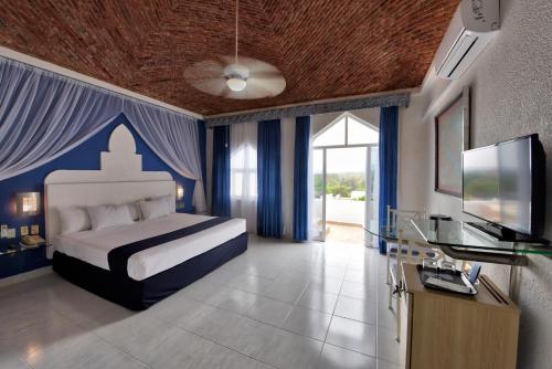 1 dormitorio con 1 cama con cortinas azules y TV en Villa Bejar Cuernavaca, en Cuernavaca