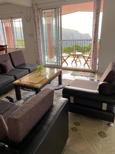 a living room with couches and a table and a balcony at Green Discovery B&B Tamarind Falls 7 Cascades in Henrietta