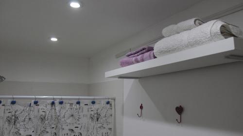 a white bathroom with purple towels on a shelf at La Tiny House in Ushuaia