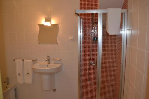 a bathroom with a sink and a shower at Hotel Comércio in Resende