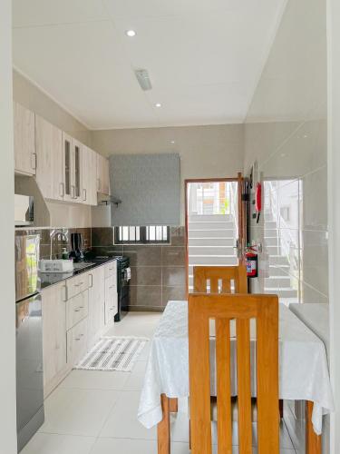 a kitchen with a table and two chairs and a kitchen with white cabinets at Palm Holiday Apartments in Grand'Anse Praslin