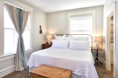 a bedroom with a white bed and two windows at Katy House Bed and Breakfast in Smithville