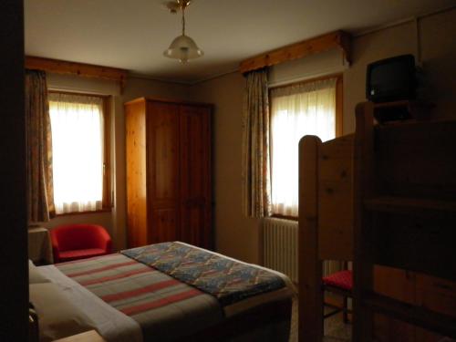 a small bedroom with a bed and two windows at Hotel Zebrù in Valfurva