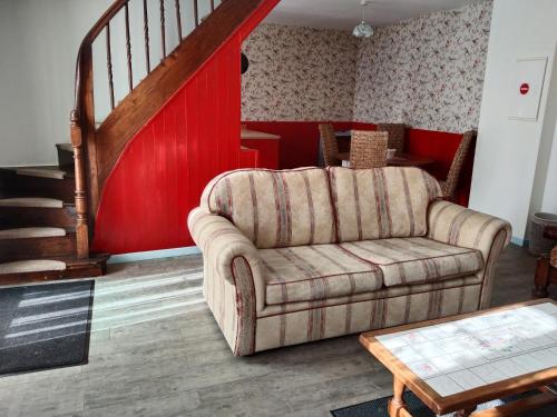 a living room with a couch and a red wall at Craftycotta in Glomel