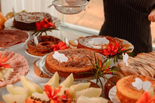 a table topped with cakes and pies and red flowers at Pouso dos Querubins in Tiradentes
