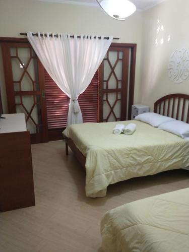 a bedroom with two beds and a window at Casarão Primavera in Serra Negra