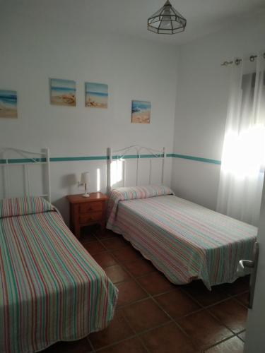 2 camas en una habitación con paredes blancas y rayas rojas y verdes en PUNTA SOL, en Isla del Moral