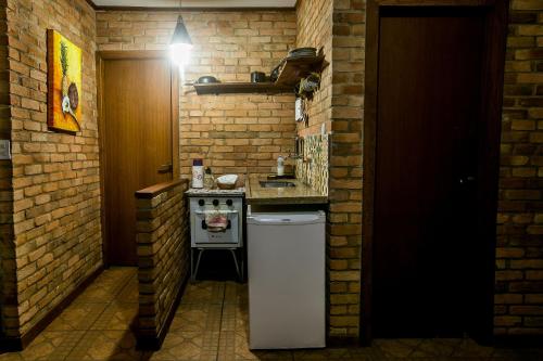 uma pequena cozinha com um fogão e um frigorífico em Chalés Belo Vale - Rua do Curro em Conceição do Ibitipoca