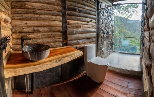baño en una cabaña de madera con lavabo y ventana en Eco Hotel Glamping El Silencio, en Santa Rosa de Cabal