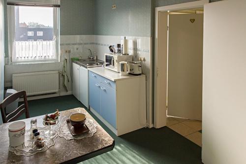 uma pequena cozinha com uma mesa e um frigorífico em Altenceller Tor, Hotel & Restaurant em Celle