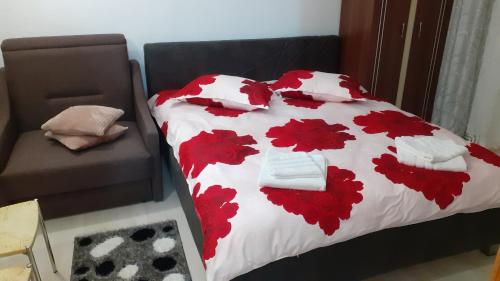 a bed with red flowers on a white comforter at Apartament ALEX-LUXURY in Târgu Ocna