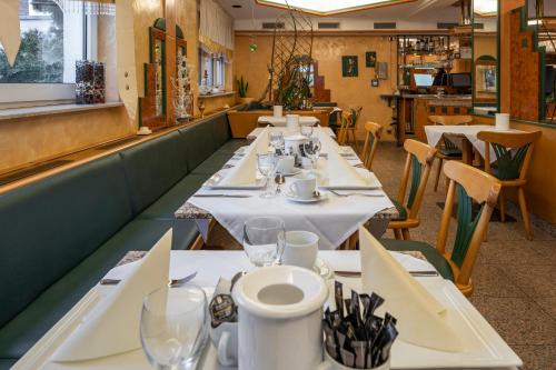 eine Reihe von Tischen in einem Restaurant mit weißer Tischwäsche in der Unterkunft Hotel Esmer in Lollar