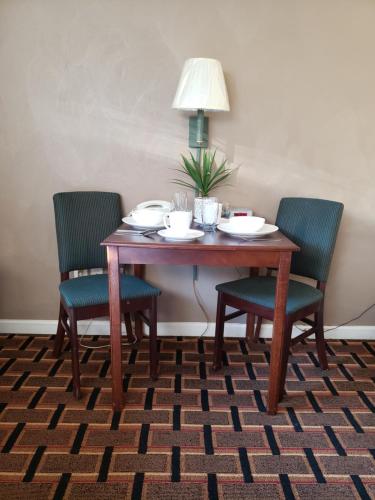 a dining room table with three chairs and a lamp at Affordable Suites Burlington in Burlington