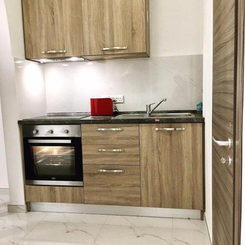 a kitchen with wooden cabinets and a sink and a stove at For Rest Aparthotel in St Paul's Bay