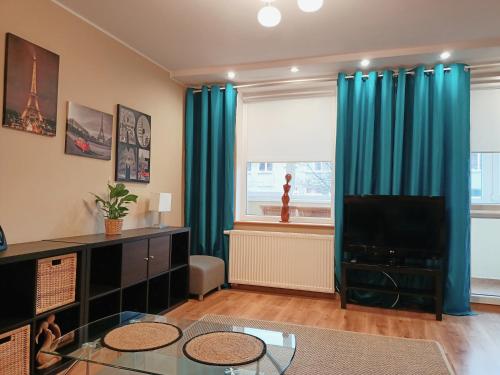a living room with blue curtains and a television at Przytulne mieszkanie blisko Galerii Bałtyckiej Zaspa in Gdańsk