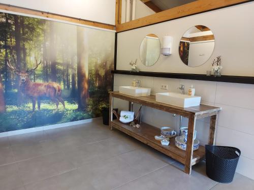 a bathroom with two sinks and a painting of a deer at Camping het Smitske in Drunen