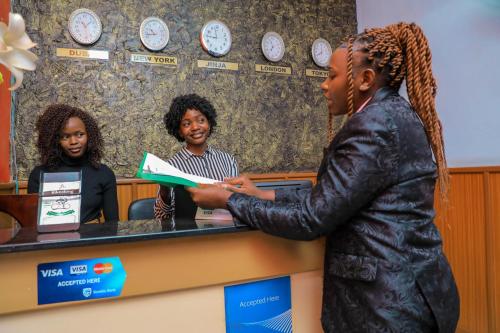 a woman is standing at a counter in a waiting room at Royal Park Hotel in Jinja
