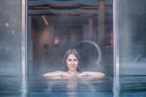 a woman is standing in a pool of water at Sporthotel Zoll in Vipiteno