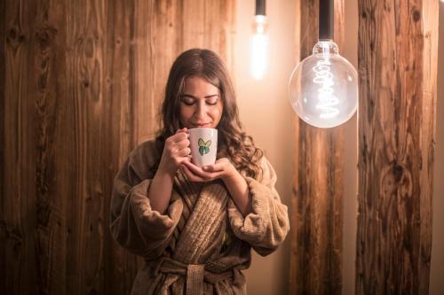 a woman holding a coffee cup in her hands at Sporthotel Zoll in Vipiteno