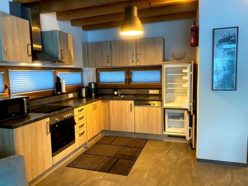 a kitchen with wooden cabinets and an open refrigerator at Mountain Apart Katzenkopf in Leutasch