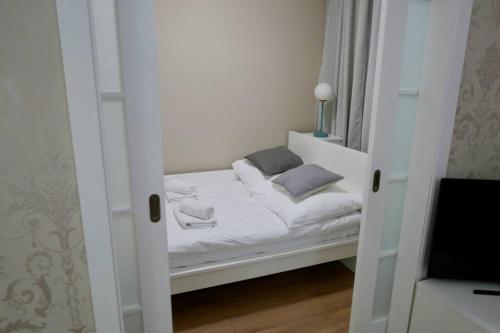 uma pequena cama branca num pequeno quarto em Kieślowskiego Apartment vis-a-vis Town Hall em Varsóvia