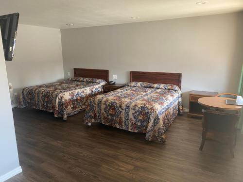 a hotel room with two beds and a table at Sun Valley Inn in Pleasant Hill