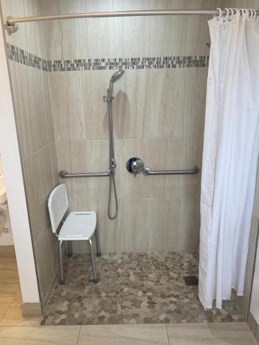 a shower with a white chair in a bathroom at Sun Valley Inn in Pleasant Hill