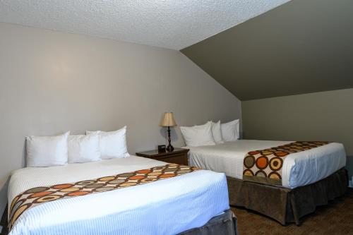 a hotel room with two beds with white sheets at Super 8 by Wyndham Cochrane in Cochrane