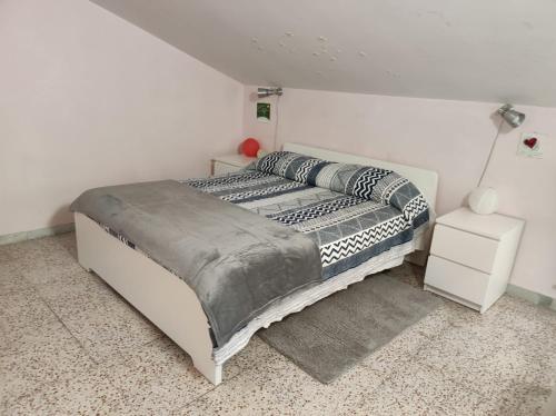 Cama blanca en habitación con mesita de noche blanca en La Mansarda, en Ascoli Piceno