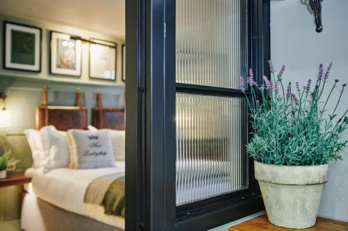 a bedroom with a bed and a potted plant next to a window at Kings Arms - Egham-Windsor in Egham