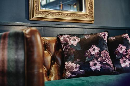 a brown leather couch with two pillows and a mirror at Kings Arms - Egham-Windsor in Egham