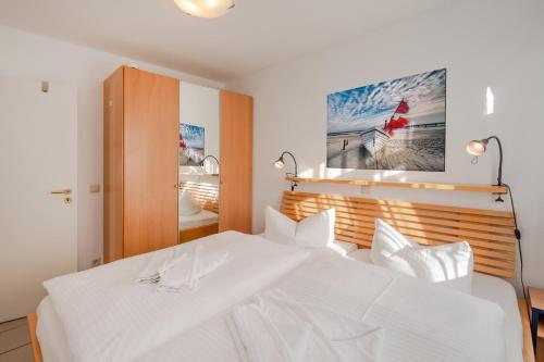 a white bed in a bedroom with a picture on the wall at Ferienwohnung Kon-Tiki, Villa Regina Maris Bansin in Heringsdorf